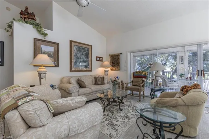 Living room featuring wood finished floors, high vaulted ceiling, and a ceiling fan