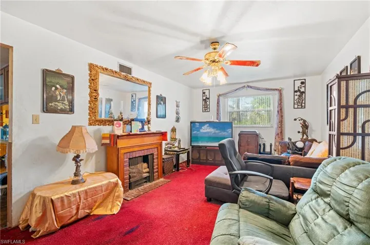 Living room with ceiling fan, a fireplace, and carpet floors
