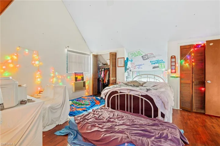 Bedroom with hardwood / wood-style floors, a closet, and vaulted ceiling