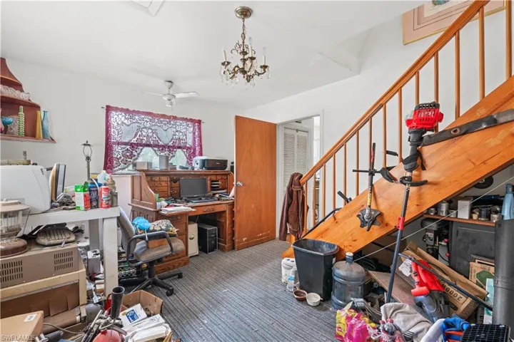 Carpeted office space with ceiling fan with notable chandelier