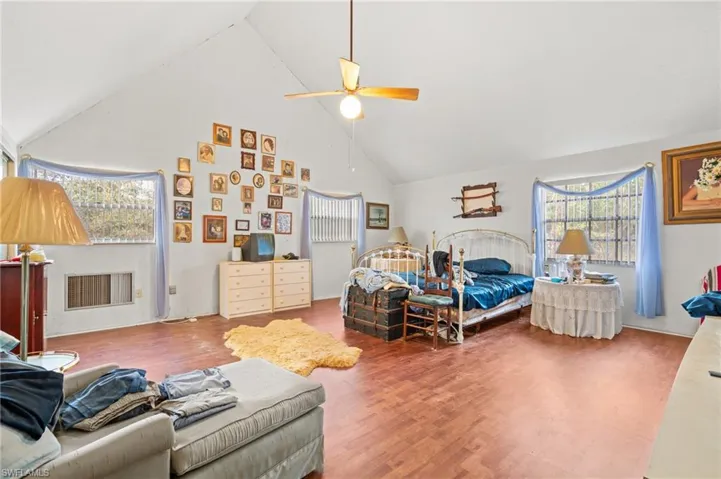 Bedroom with ceiling fan, wood-type flooring, and high vaulted ceiling
