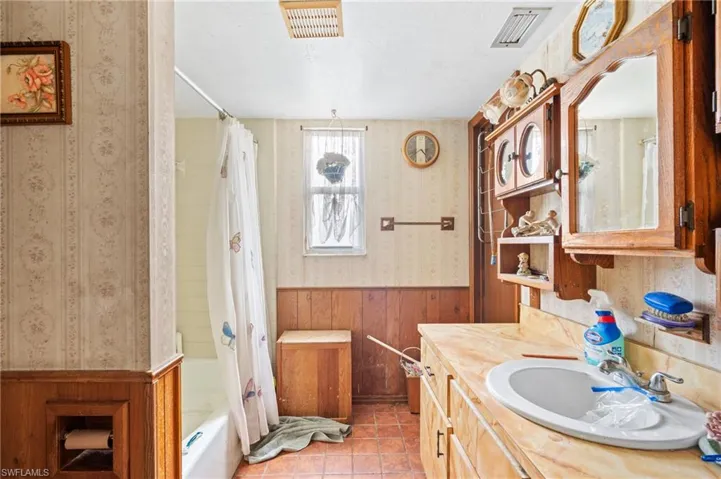 Bathroom with vanity, tile patterned floors, shower / bath combo, and wood walls