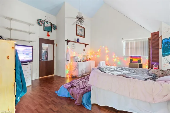 Bedroom featuring ceiling fan, dark hardwood / wood-style floors, and high vaulted ceiling