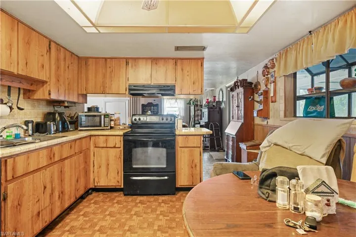 Kitchen featuring sink, black range with electric stovetop, tasteful backsplash, and light parquet flooring