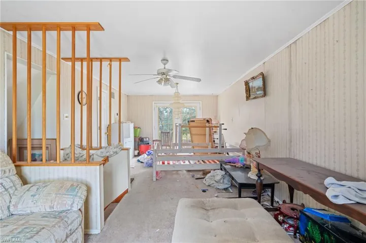Carpeted living room with ceiling fan and crown molding
