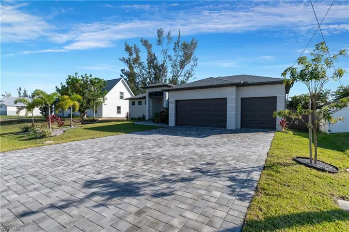 View of front of property with a garage and a front lawn