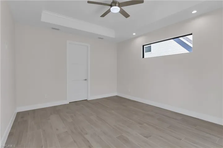 Empty room featuring ceiling fan, light hardwood / wood-style floors, a raised ceiling, and ornamental molding