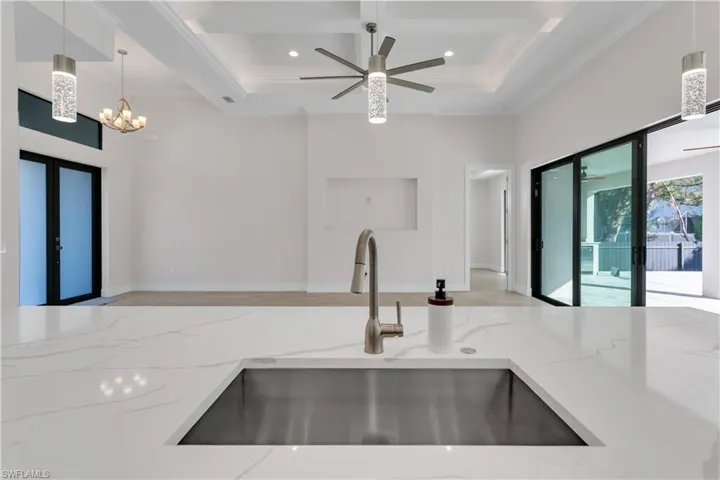 Kitchen with light stone counters, french doors, hanging light fixtures, and sink