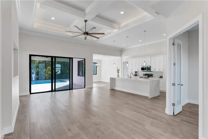 Unfurnished living room with ceiling fan, beamed ceiling, light hardwood / wood-style floors, and coffered ceiling