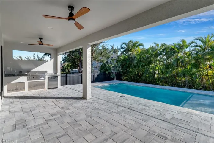 View of swimming pool with area for grilling, ceiling fan, sink, grilling area, and a patio