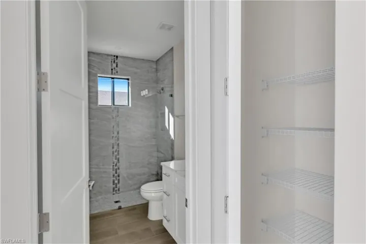 Bathroom with tiled shower, vanity, and toilet