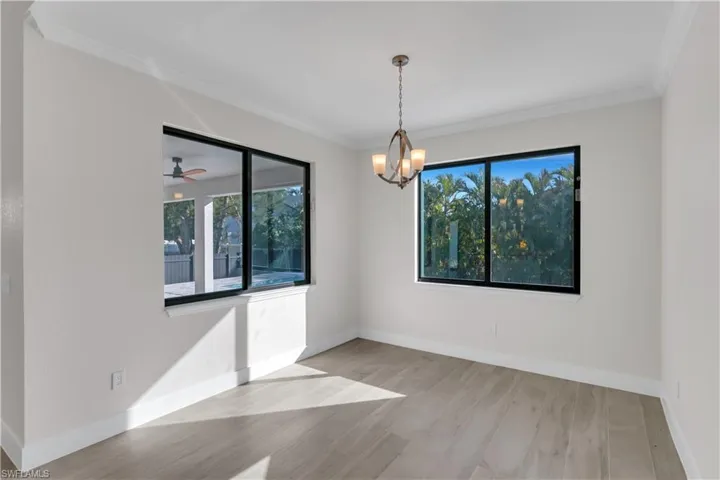 Unfurnished room featuring ceiling fan with notable chandelier, light wood-type flooring, and ornamental molding