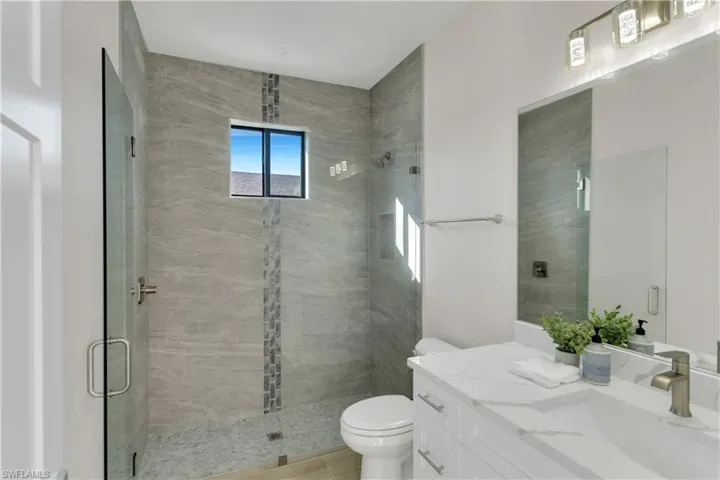 Bathroom featuring tile patterned flooring, vanity, a shower with shower door, and toilet