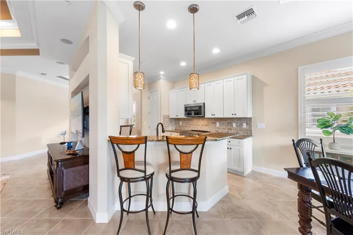 This kitchen and dining design offers a bar area, eat-in-kitchen on one side, and a separate dining area open on the other side, making it ideal for entertaining.
