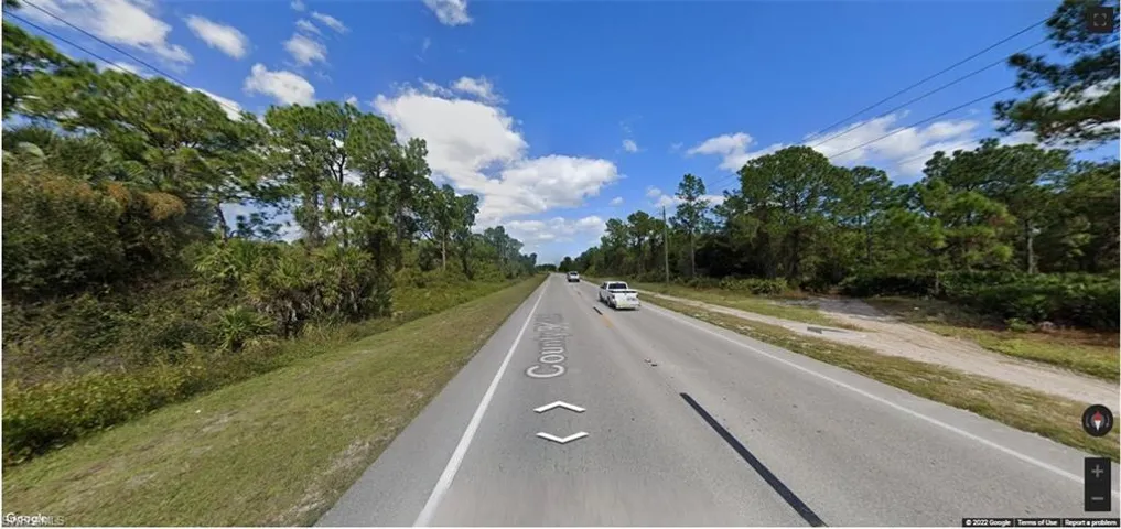 View of asphalt road with view of wooded area
