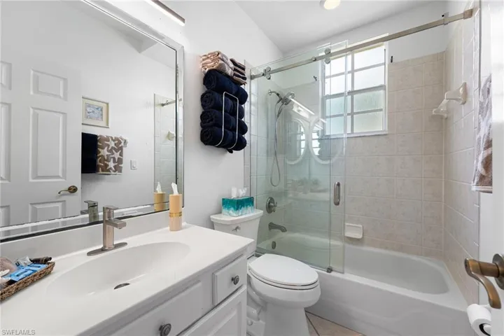 The second full bath features stylish barn-door sliders, an enclosed shower and tub combination, along with custom lighting and mirrors for a refined finish.