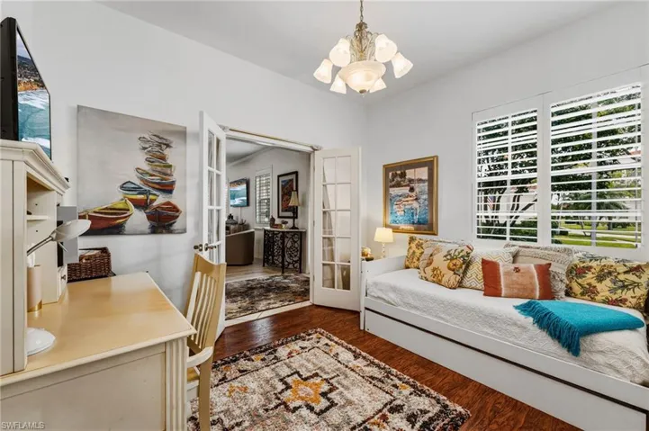 The third bedroom, currently set up with a daybed, also functions as a versatile office or den and features glass French doors for added privacy. Wood flooring and plantation shutters complete the space with warmth and style.