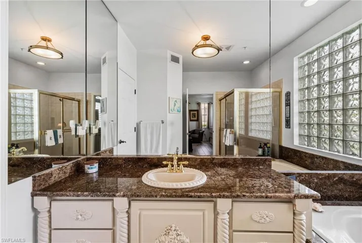 The primary bath features granite countertops, custom cabinetry, elegant mirrors, a private water closet, and a spacious walk-in closet.