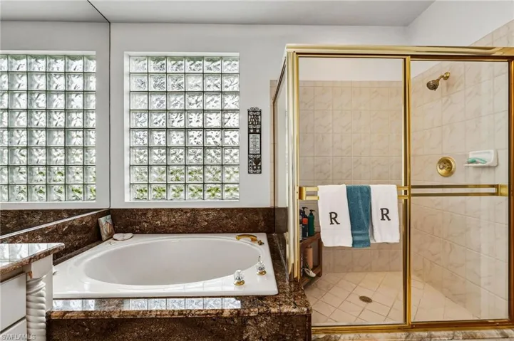 The primary bath features a relaxing garden-style soaking tub and a separate walk-in shower, filled with abundant natural light—an ideal retreat to unwind after a long day on the links.