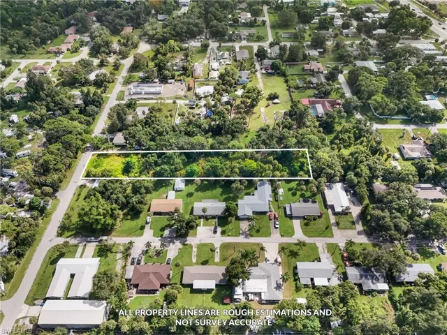 Aerial view of residential area featuring a tree filled landscape and property parcel outlined
