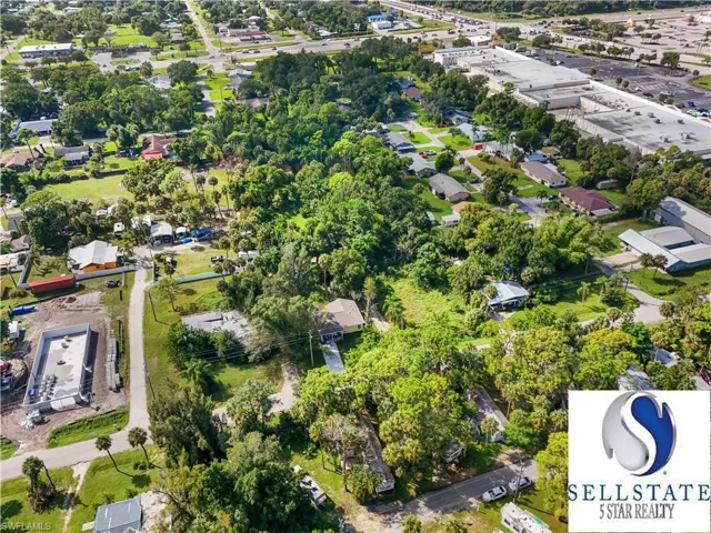 Aerial view of property's location featuring nearby suburban area and a tree filled landscape