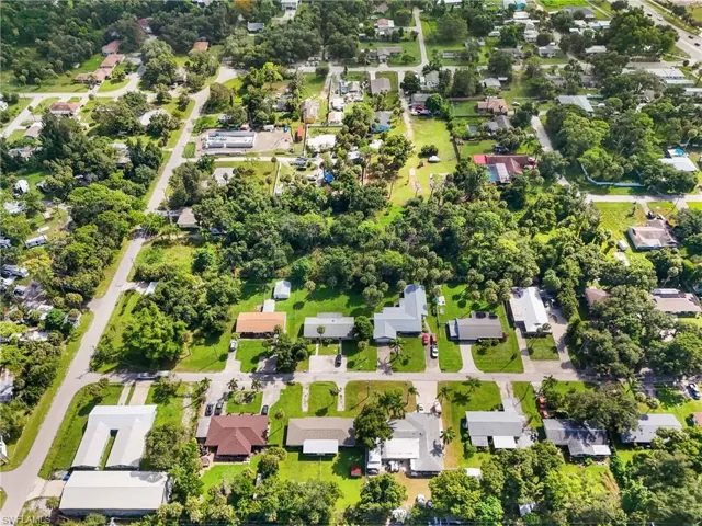 Aerial view of property and surrounding area with nearby suburban area and a tree filled landscape