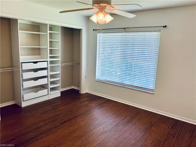 Unfurnished bedroom featuring a closet, ceiling fan, dark hardwood / wood-style flooring, and multiple windows
