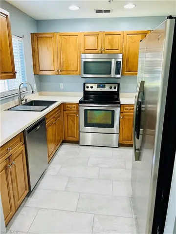 Kitchen with stainless steel appliances, light tile flooring, and sink