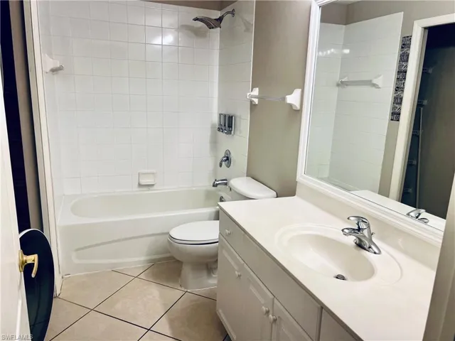 Full bathroom featuring tile flooring, toilet, oversized vanity, and tiled shower / bath