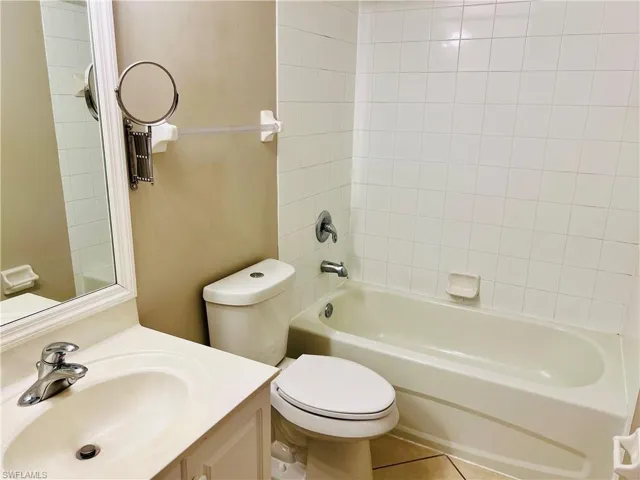 Full bathroom featuring tile floors, vanity, toilet, and tiled shower / bath combo