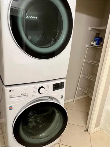 Laundry room featuring stacked washing maching and dryer and light tile floors