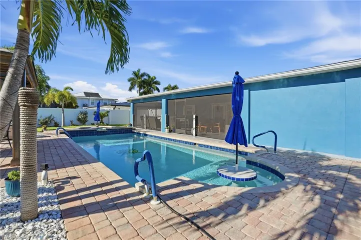 View of swimming pool featuring a patio area, a sunroom, a fenced backyard, and a pool with connected hot tub - Virtually Edited Image