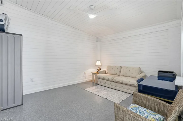 Flex room with vaulted ceiling, wood ceiling, a ceiling fan, and wooden walls - Virtually Edited Image