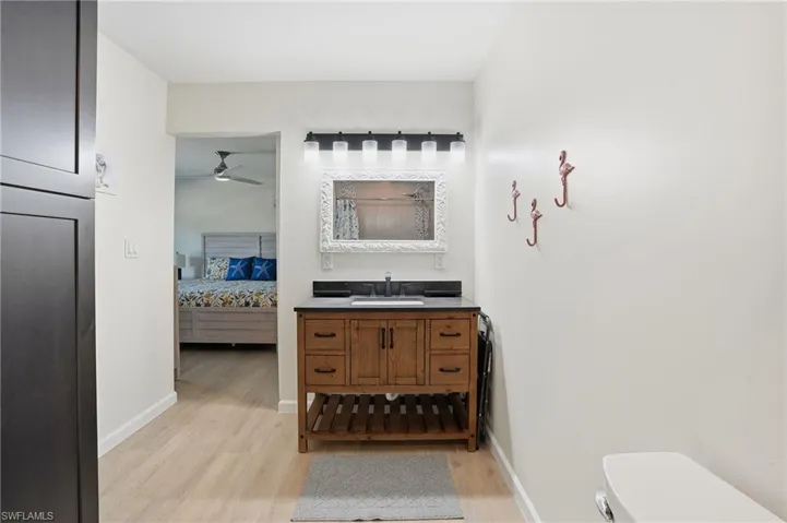 Full bath with vanity, light wood tile flooring, connected bathroom, and a ceiling fan - Virtually Edited Image