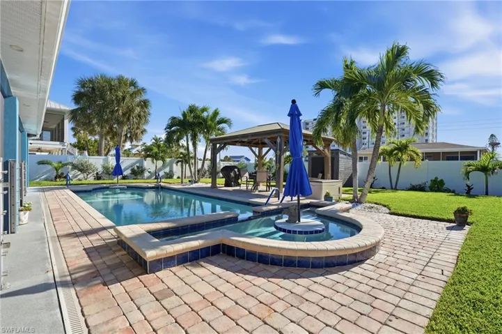 View of swimming pool featuring a fenced backyard, a patio, a gazebo, and a pool with connected hot tub - Virtually Edited Image