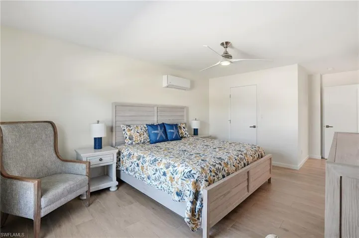 Bedroom with wood tile floors and a ceiling fan - Virtually Edited Image