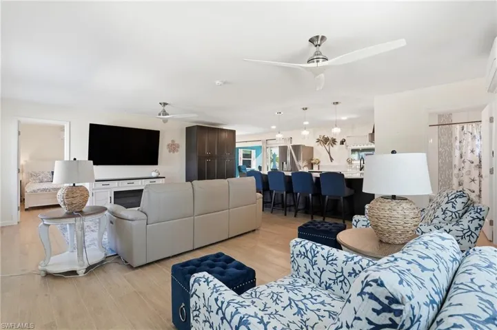 Living room featuring ceiling fan and light wood tile floors - Virtually Edited Image