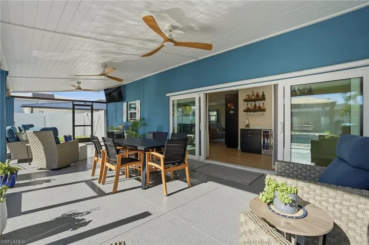 Sunroom / solarium with outdoor dining space, an outdoor living space, ceiling fan, and a patio area - Virtually Edited Image