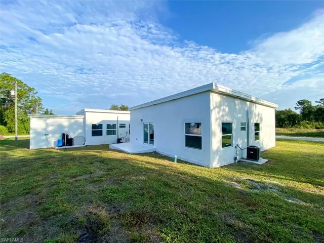 Rear view of house with a yard, stucco siding, and a patio
