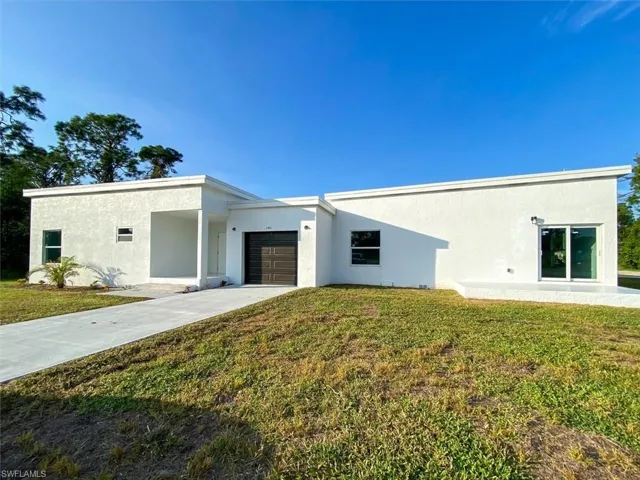 View of front of property featuring a garage, stucco siding, concrete driveway, and a front lawn