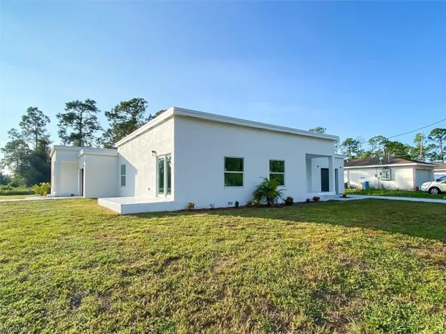 View of side of property featuring a lawn and stucco siding
