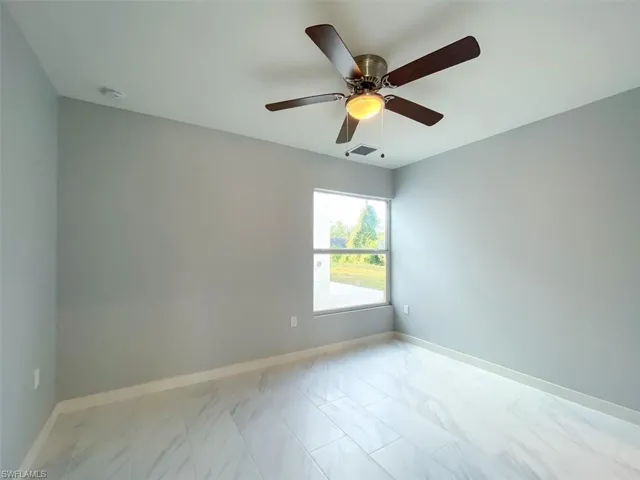 Unfurnished room with light marble finish floors and ceiling fan