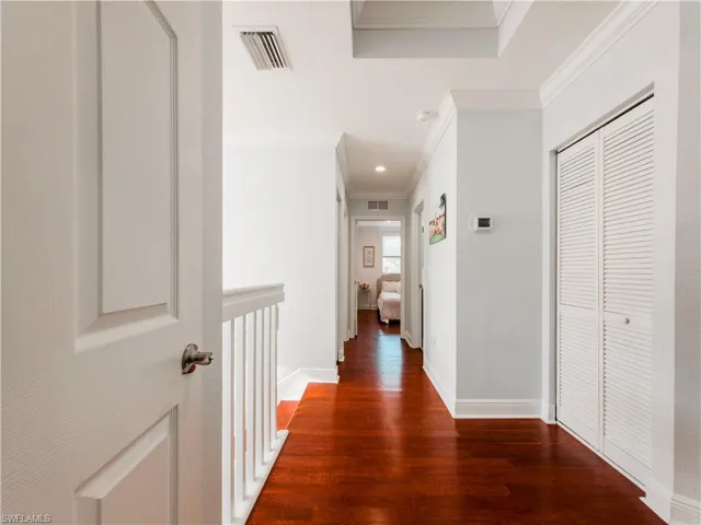Corridor with ornamental molding and dark wood-style flooring