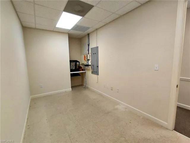 Utility room with light flooring, a paneled ceiling, and electric panel