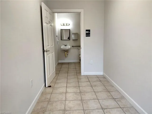 Hall to Half bath featuring toilet and light tile patterned floors