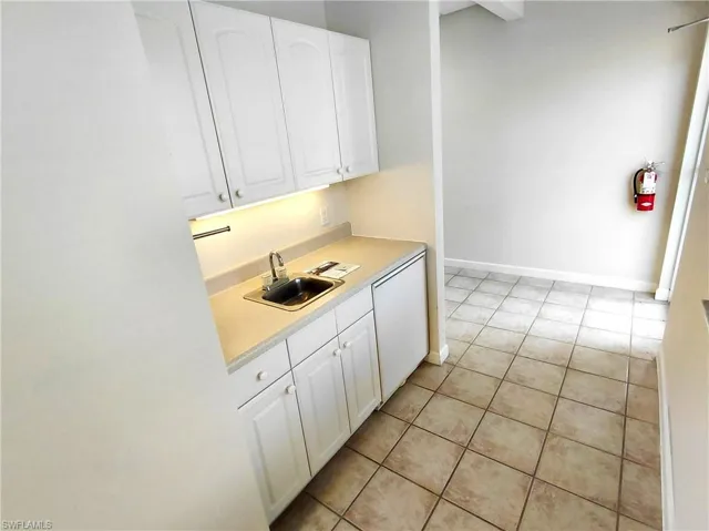 Kitchen featuring white cabinets, light countertops, light tile patterned floors, and dishwasher