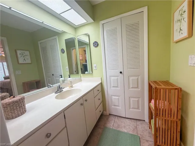 Bathroom with a closet, vanity, and light tile patterned floors
