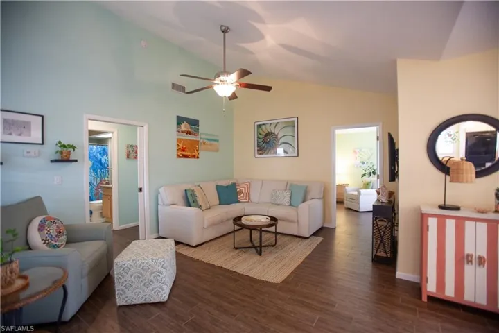 Living area with lofted ceiling, dark wood finished floors, and a ceiling fan