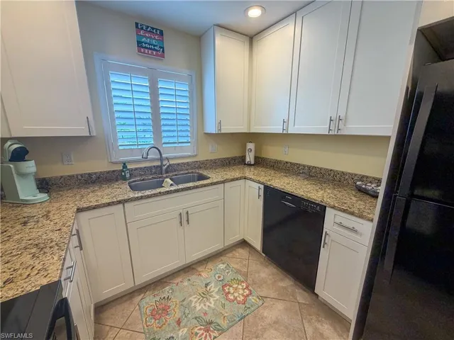 Kitchen with white cabinetry, black appliances, light stone countertops, light tile patterned floors, and recessed lighting