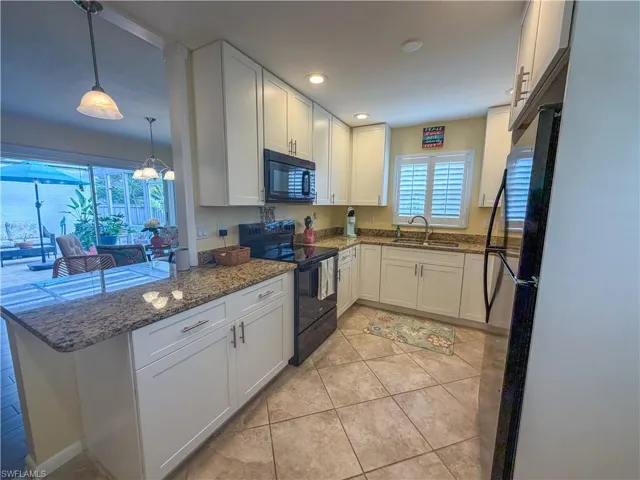 Kitchen with white cabinets, black appliances, dark stone counters, healthy amount of natural light, and recessed lighting